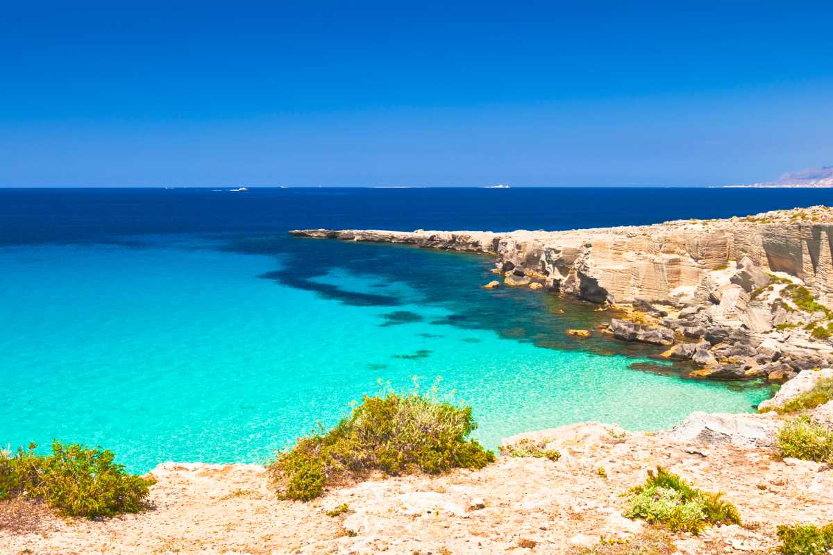 Vista panoramica dell'aeroporto di Lampedusa con atterraggio di un aereo e il mare sullo sfondo, atmosfera estiva e accogliente